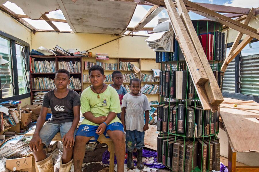 Fijian children sitting in the wreckage of their classroom after it was destroyed by Tropical Cyclone Yasa.