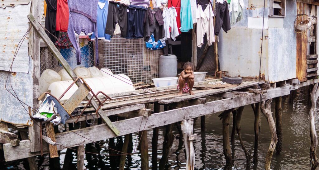 A child sits on the porch of a house on stilts in an informal settlement in Port Moresby, Papua New Guinea.