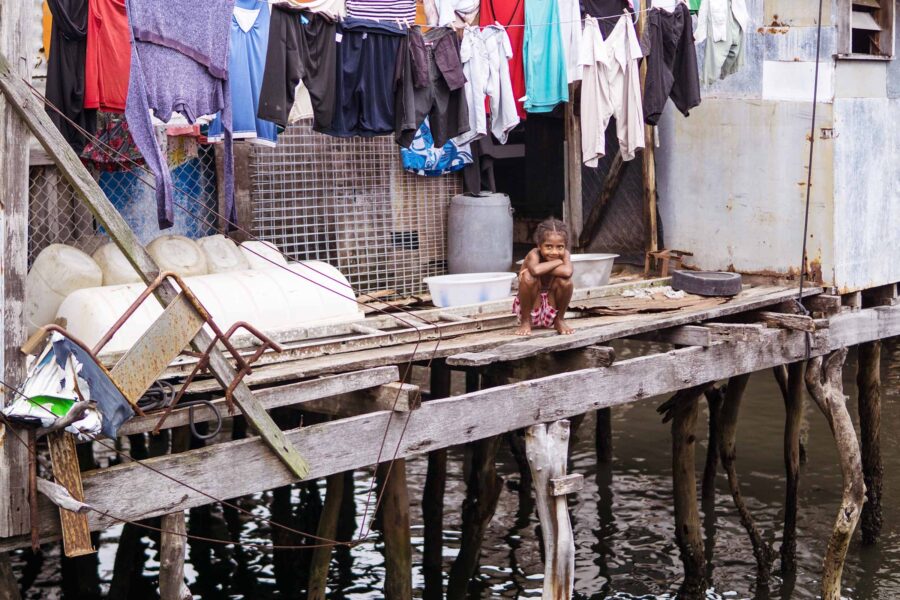 A child sits on the porch of a house on stilts in an informal settlement in Port Moresby, Papua New Guinea.