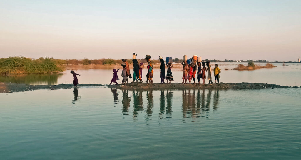 Women and girls walking with their buckets to fetch water in the inundated region of Geokaloi village in the Southern Pakistani province of Sindh.
