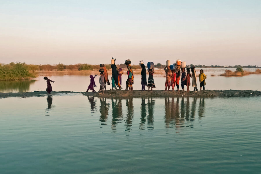 Women and girls walking with their buckets to fetch water in the inundated region of Geokaloi village in the Southern Pakistani province of Sindh.